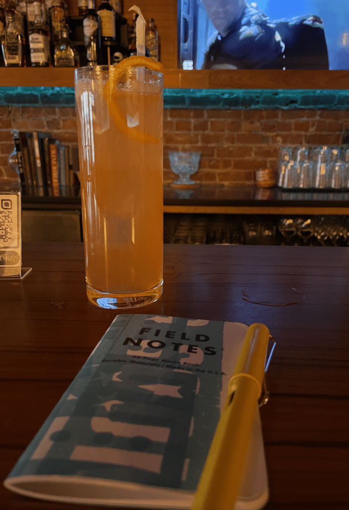 Field notes at a bar with a cocktail.